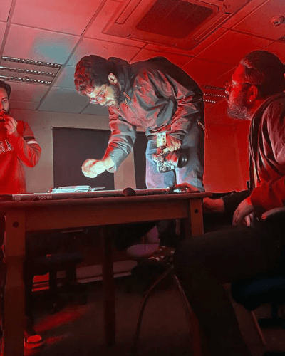 Man in red shirt lit by neon overhead ceiling lights.