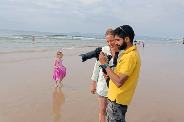 Two filmmakers on beach with ocean backdrop.